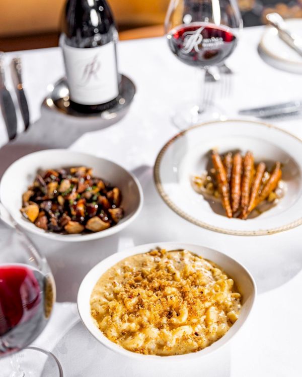 A plated meal spread on a table with bowls of food and two wine glasses, ready for dining.