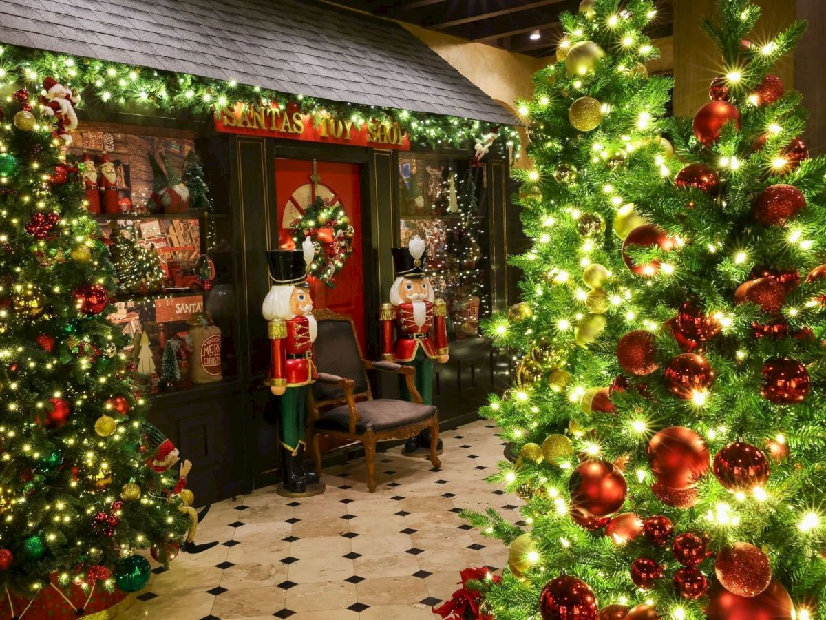 A festive mall entrance with a &ldquo;Santas Toy Shop&rdquo; sign, towering Christmas trees, twinkling lights, and nutcracker figures by the doorway.